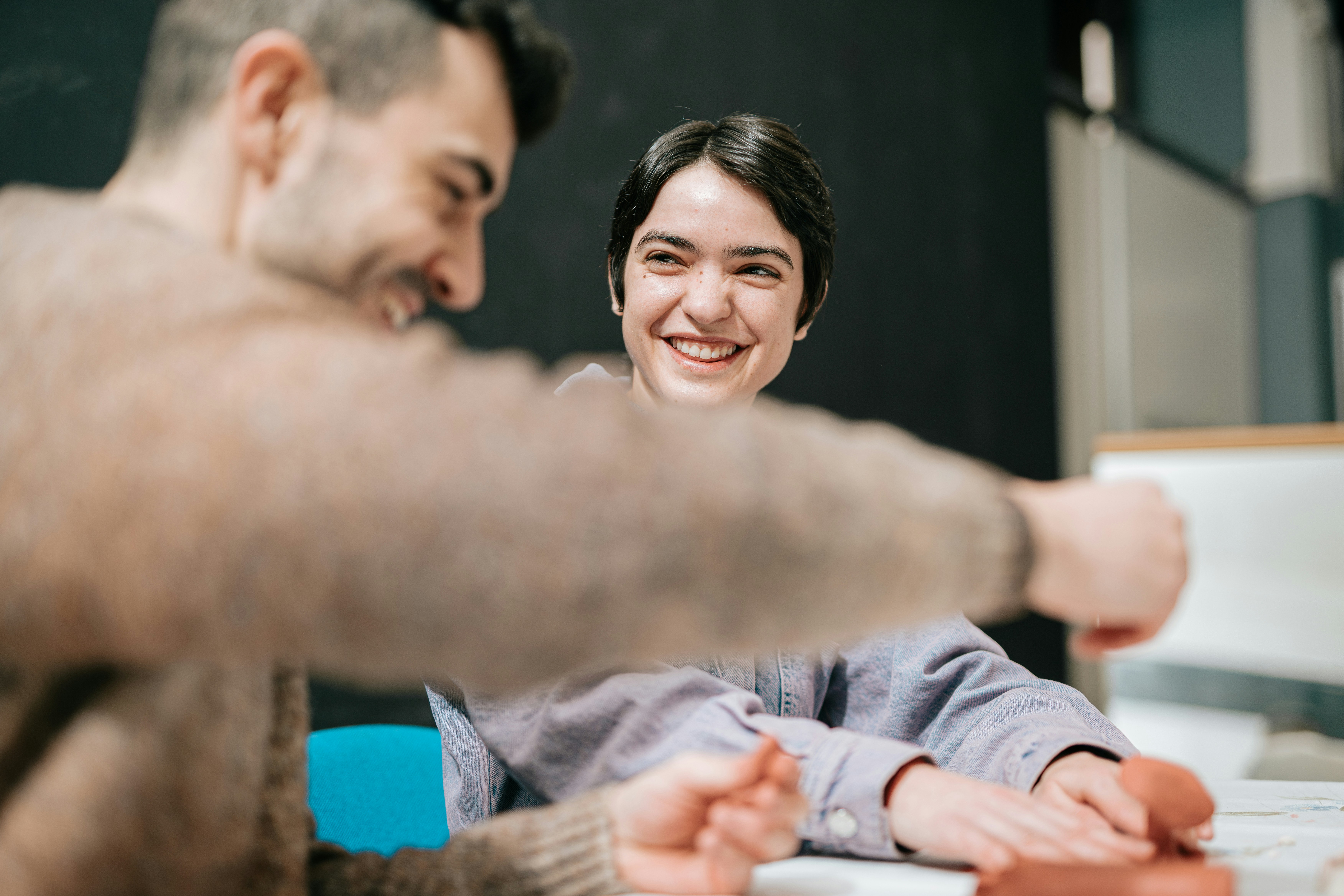 Two people in a pottery workshop laughing