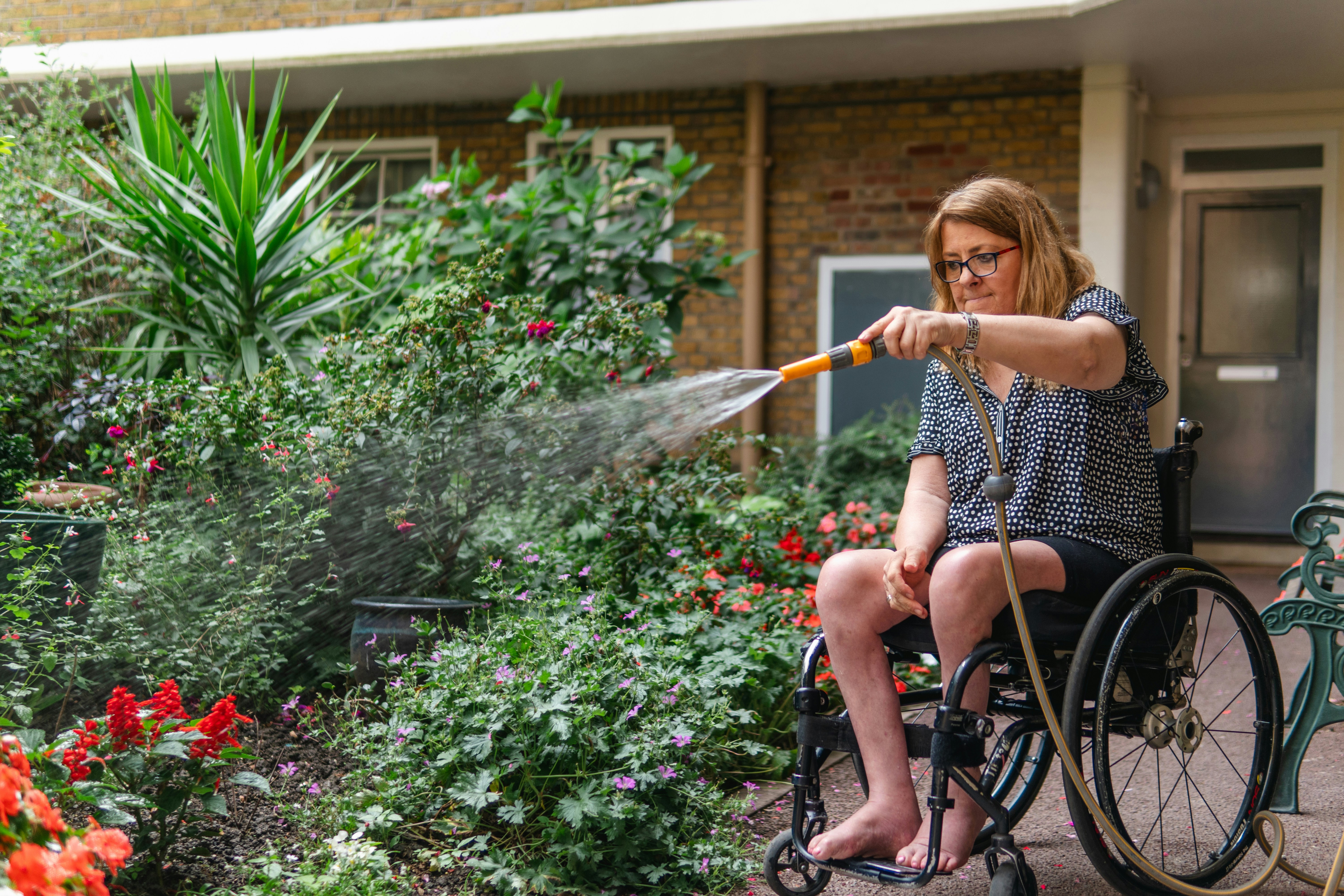 person in wheelchair watering the garden