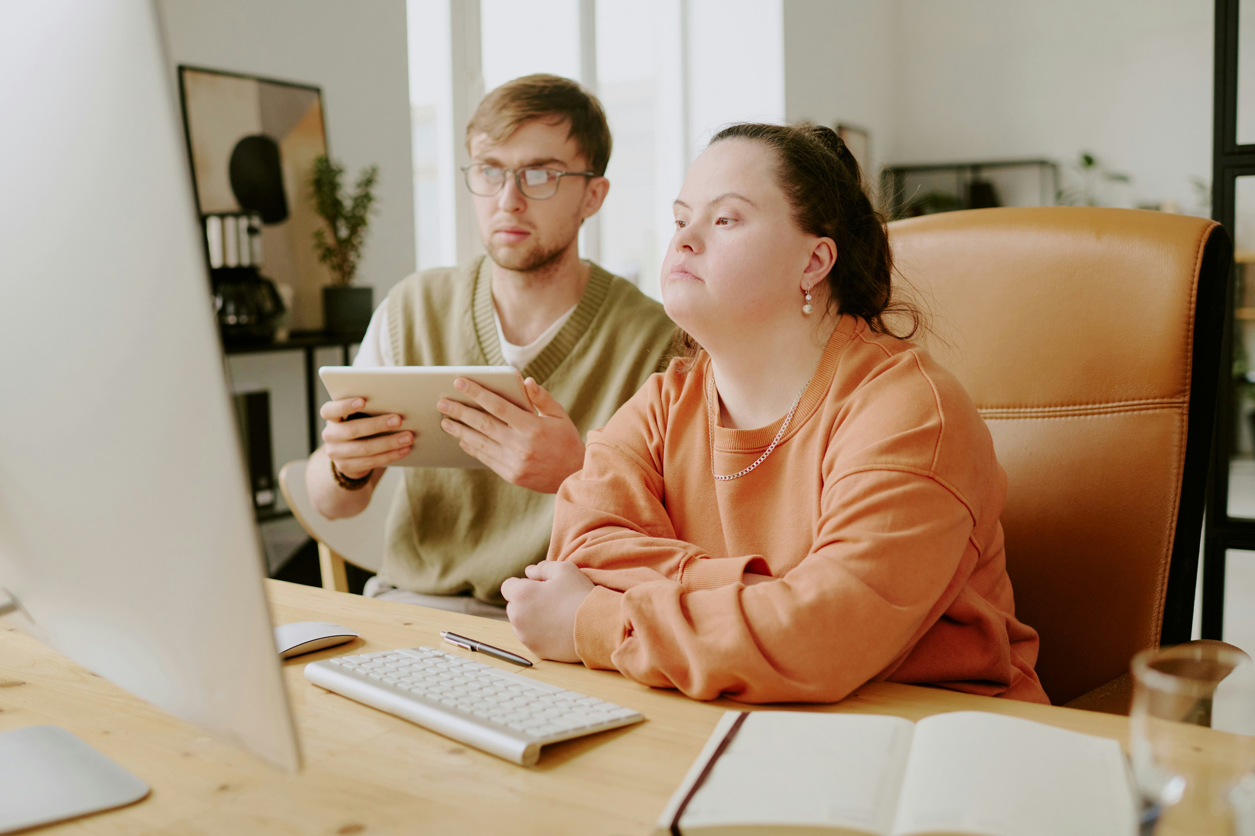 two people at a desk looking at a computer