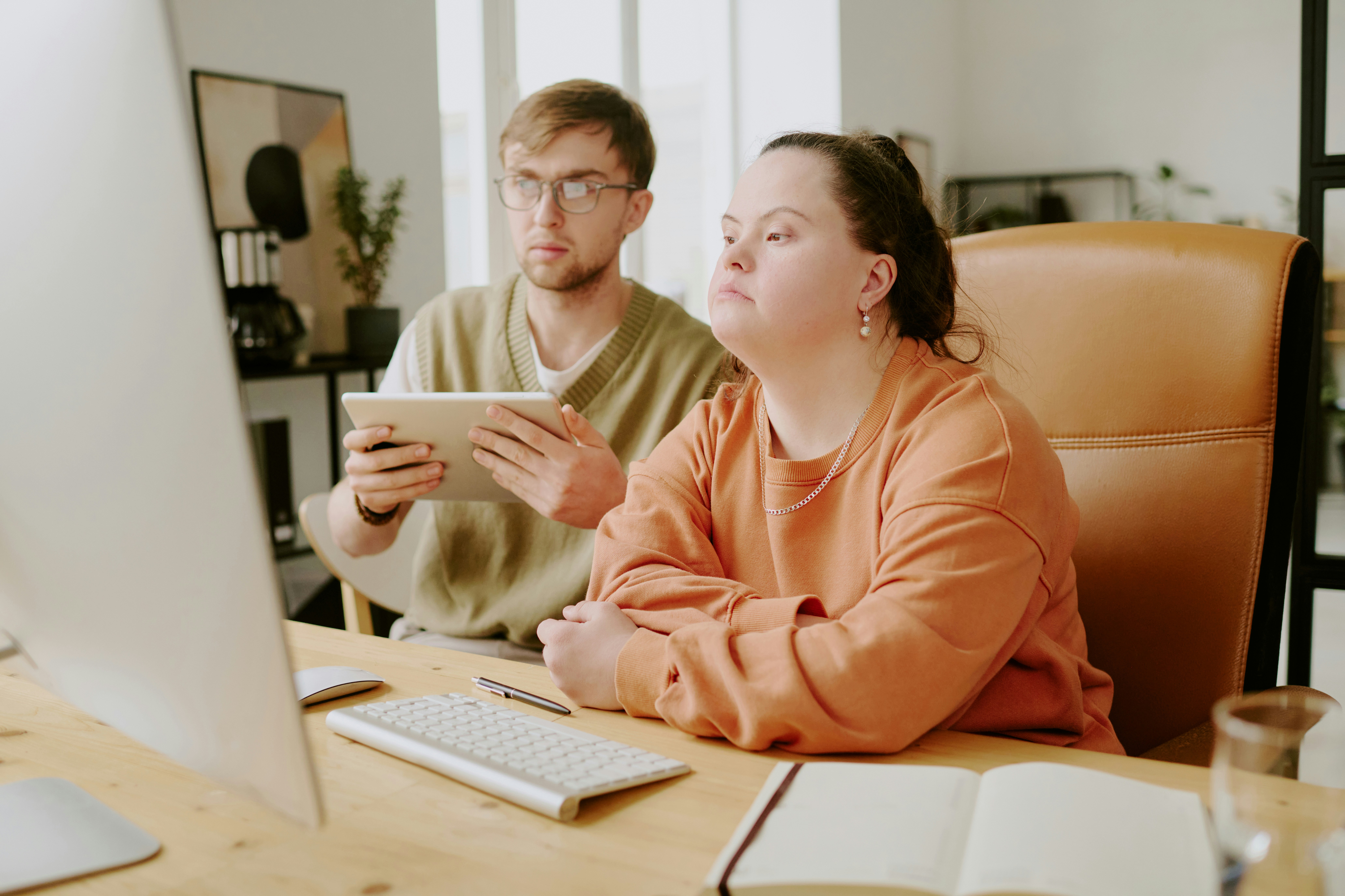 two people at a desk looking at a computer