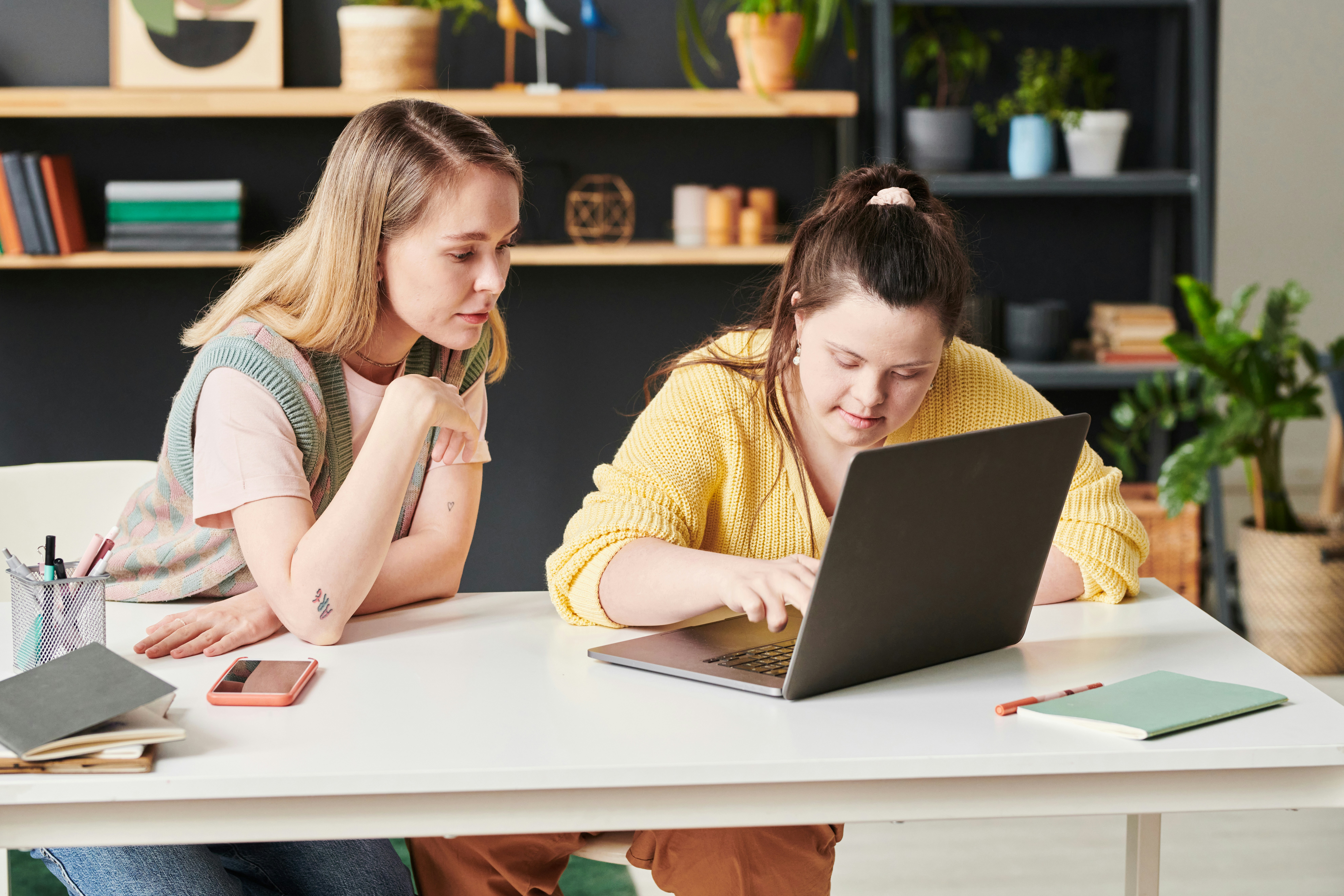 two people sat at a table looking at a laptop