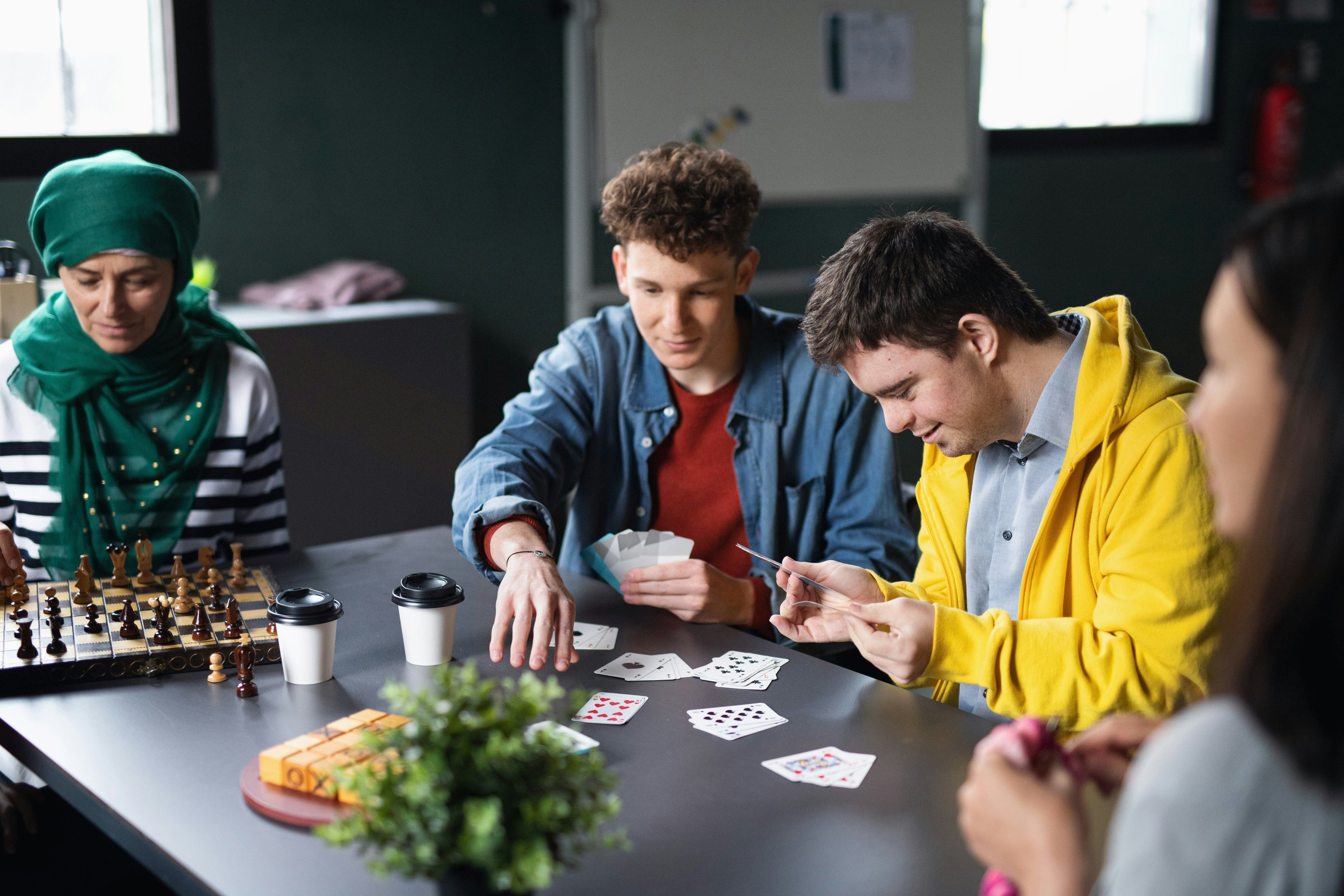 A group of happy people playing cards and board games in a community centre.