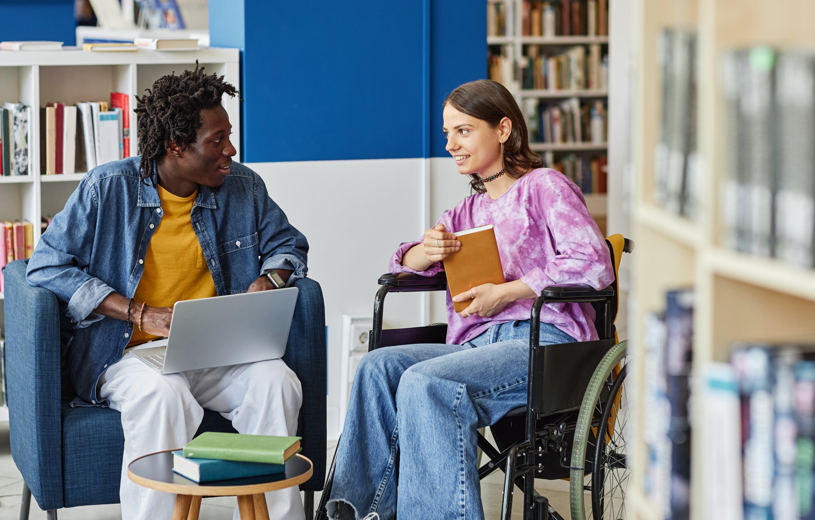 Person in wheelchair talking to person with laptop