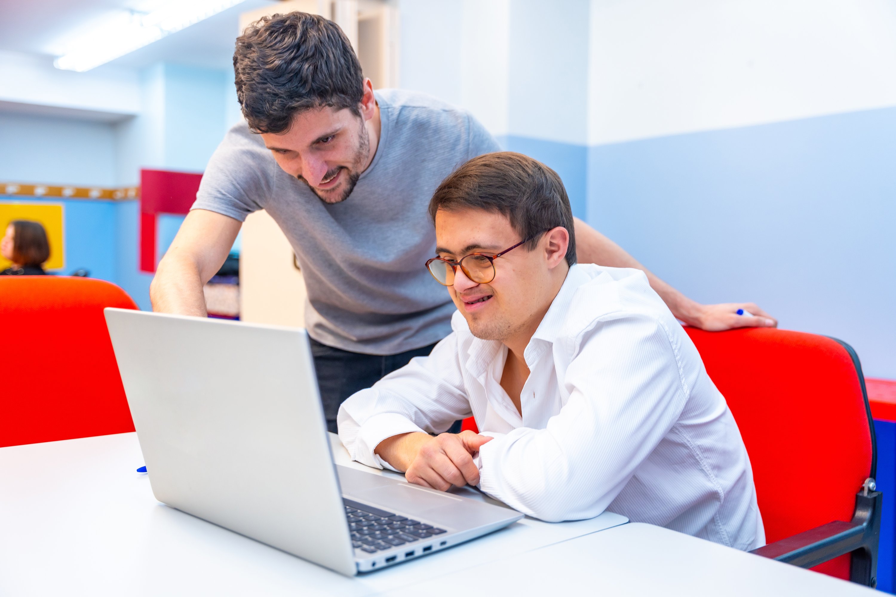 Service user on a laptop with person helping them