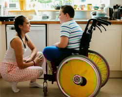 support worker leaning down to speak with a child in wheelchair