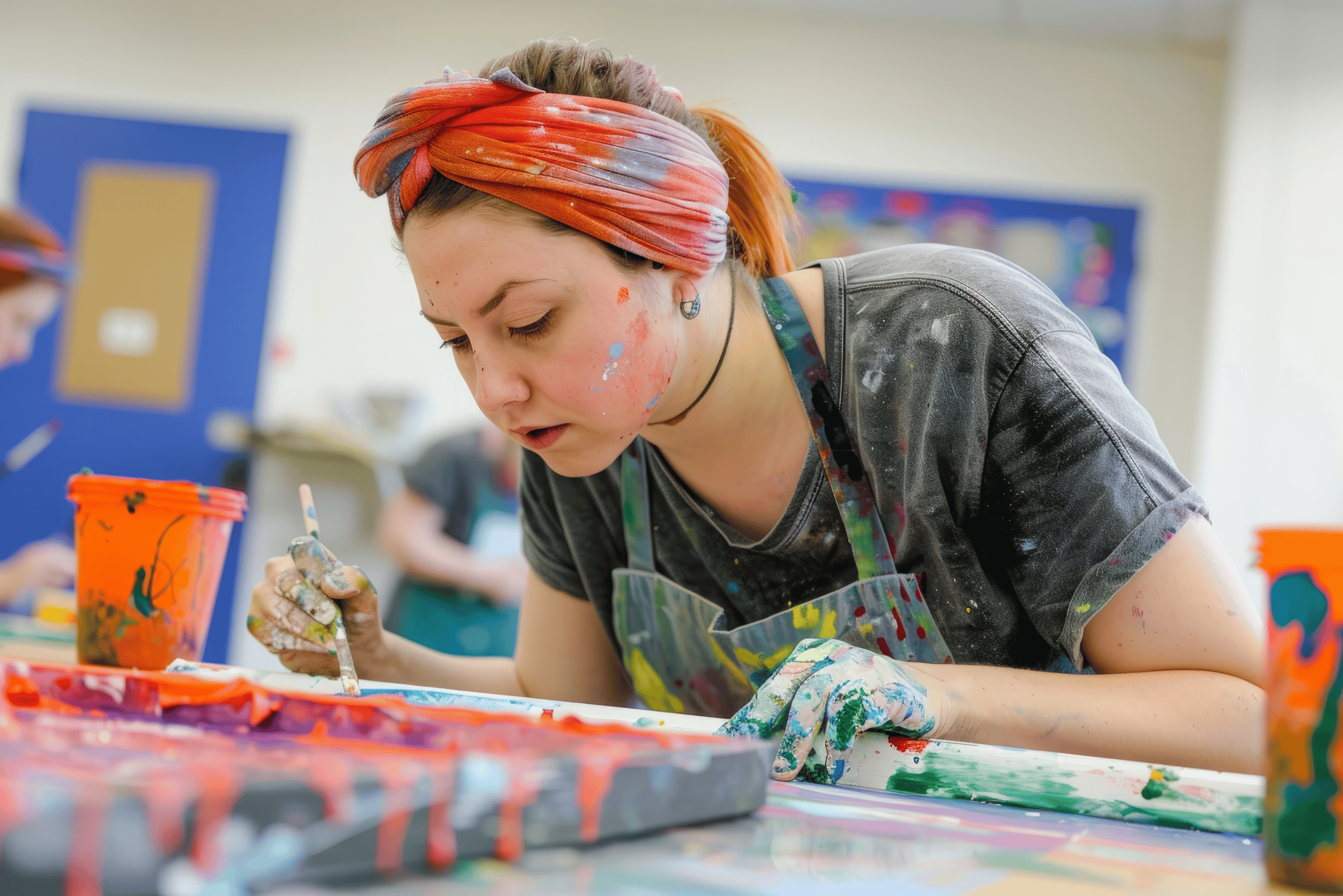A woman painting. She is wearing a headband and her hands are covered in paint. 